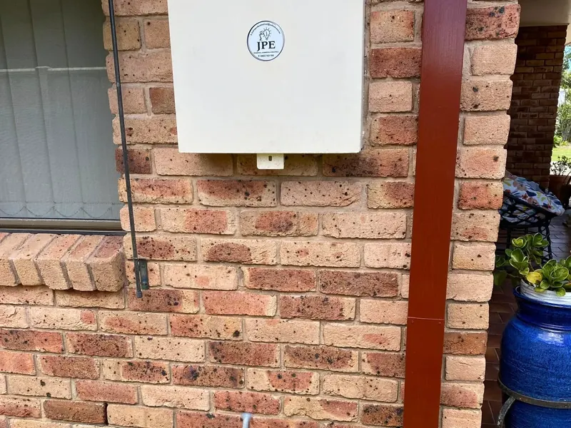 A newly installed switchboard enclosure mounted on the brick wall of a house